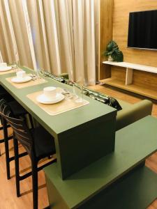 une table verte avec des assiettes et des tasses dessus dans l'établissement Hot Beach Suites - Apartamento, à Olímpia