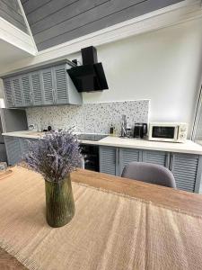 a kitchen with a table and a vase with purple flowers at Black Dora in Yaremche