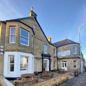 un edificio con mesas de picnic delante de él en The Fig Tree Markinch, Glenrothes en Markinch