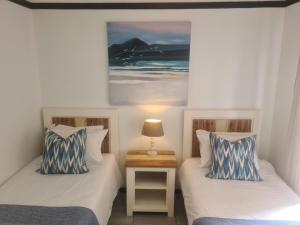 a bedroom with two beds and a lamp on a table at Plett Sunrise:) in Plettenberg Bay