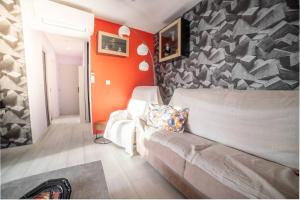 a living room with a couch and an orange wall at Le Central Vue Mer Clim Plage 2min Cosy Confort - Jetservices Conciergerie in La Grande-Motte