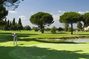 a man is playing golf on a golf course at Le Central Vue Mer Clim Plage 2min Cosy Confort - Jetservices Conciergerie in La Grande-Motte