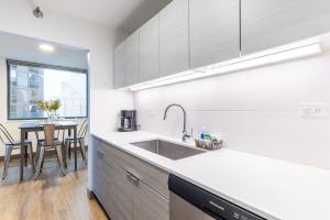 een witte keuken met een wastafel en een tafel bij ENVITAE 3BR Luxury Corner Loft with Navy Pier Views in Chicago