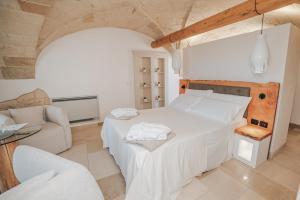 1 dormitorio con 1 cama blanca grande y 1 sofá en Masseria Longa Boutique Hotel, en Otranto