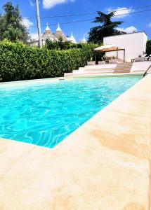 una piscina de agua azul frente a una casa en Trulli and Pool - I Cactus, en Martina Franca