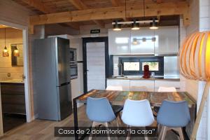 eine Küche mit einem Tisch und Stühlen sowie einem Kühlschrank in der Unterkunft NidoGredos Cabañas Ecológicas de Diseño in El Tiemblo
