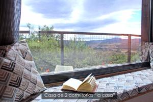ein Fenster mit einem Buch auf einem Bett mit Aussicht in der Unterkunft NidoGredos Cabañas Ecológicas de Diseño in El Tiemblo
