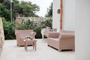 een patio met stoelen en tafels en een stenen muur bij La Vacia Boutique Country Resort in Pulsano