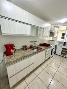 cocina con armarios blancos y fregadero rojo en Apartamento em Arraial do Cabo, en Arraial do Cabo