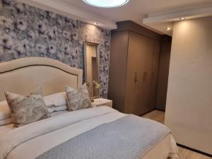 a bedroom with a white bed with a floral wallpaper at Soho Luxury Penthouse in Sandton
