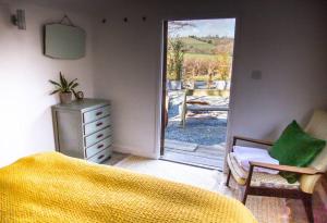 a bedroom with a bed and a door to a patio at The Deckhouse, cabin with big deck nr Hay-on-Wye in Rhos-gôch