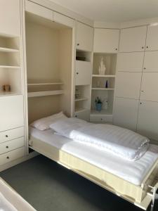 a white room with a bed and white cabinets at Dünenrose 21 in Norderney