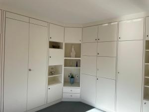 a white wardrobe in a room with white cabinets at Dünenrose 21 in Norderney