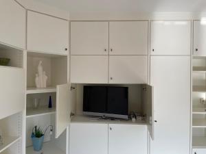 a living room with white cabinets and a tv at Dünenrose 21 in Norderney +8 photos