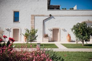 a white building with doors and flowers in the yard at Masseria Longa Boutique Hotel in Otranto