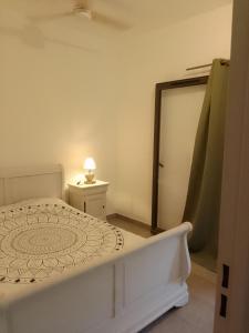 - une chambre blanche avec un lit et un miroir dans l'établissement LE VÉTIVER Cosy Appartement proche Aéroport, à Sainte-Marie