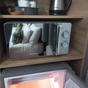 a microwave on a shelf with a couch in it at Cronin Luxury Accomodation Room 3 in Kimberley