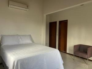 1 dormitorio con 1 cama blanca y 1 silla en Pássaros, en Mata de Sao Joao