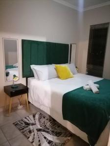 a bedroom with a large bed with a green headboard at Peaceful Home with Sbo in Pietermaritzburg