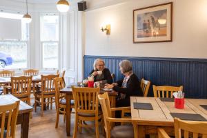 Dos mujeres sentadas en mesas en un restaurante en The Fig Tree Markinch, Glenrothes en Markinch