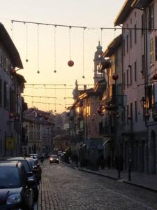 une rue de la ville avec des lumières de Noël et des voitures garées dans l'établissement Casa vacanze "LaVitaÈAdesso!", à Bergame
