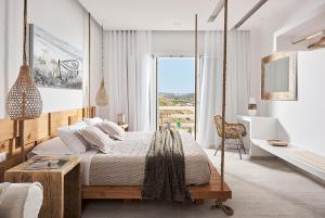 a bedroom with a swing bed and a desk at Nirome Luxury Suites in Adamantas