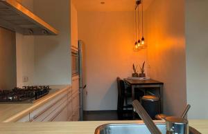 a kitchen with an orange wall and a stove top oven at Op de koule in Klimmen