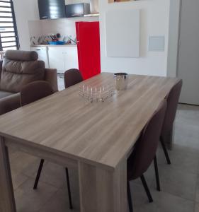 a wooden table in a living room with chairs at LE VÉTIVER Cosy Appartement proche Aéroport in Sainte-Marie