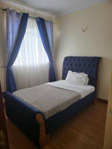 łóżko z niebieskim zagłówkiem w pokoju z oknem w obiekcie Vacay interprime villa #10 w mieście Kitengela 