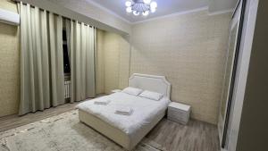 um quarto com uma cama branca e uma janela em Апартамент NUR em Bishkek