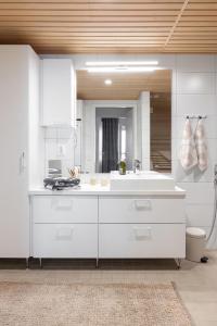 uma cozinha branca com um lavatório e um espelho em Top, cozy, lakeside, sauna and free indoor parking em Tampere