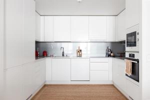 een witte keuken met witte kasten en apparaten bij Top, cozy, lakeside, sauna and free indoor parking in Tampere