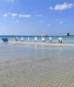 un grupo de sillas y una sombrilla en una playa en Villa delle Stelle con piscina, en Leverano