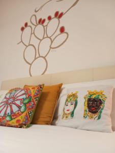 ジャルディーニ・ナクソスにあるB&B fragranza di siciliaのベッドの上に枕2つ、壁に花