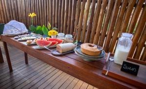 uma mesa com comida e bebidas num deque de madeira em Bella Rosa Noronha em Fernando de Noronha