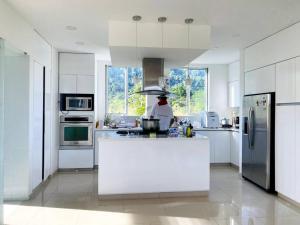 a kitchen with white cabinets and a man preparing food at Hermosa casa campestre! in Ibagué