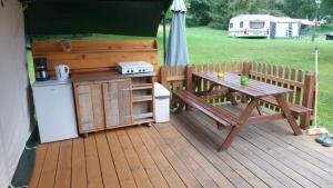 een houten terras met een picknicktafel en een fornuis bij Safari tent in Magyarhertelend