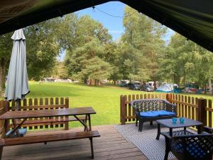 een houten terras met een picknicktafel en een parasol bij Safari tent in Magyarhertelend