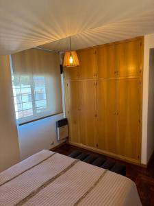 a bedroom with a bed and wooden cabinets at DEPARTAMENTO Céntrico MENDOZA in Mendoza