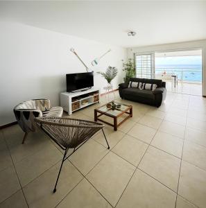 ein Wohnzimmer mit einem Sofa und einem TV in der Unterkunft Appartements T3 standing Vue mer époustouflante à quelques pas de la plage in Les Trois-Îlets