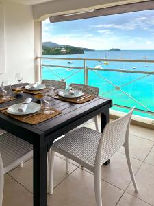 een eettafel met stoelen en uitzicht op de oceaan bij Appartements T3 standing Vue mer époustouflante à quelques pas de la plage in Les Trois-Îlets