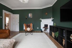 un soggiorno con pareti verdi, una sedia e una TV di Trendy 2 Bed Flat - Near Airport a Broxburn