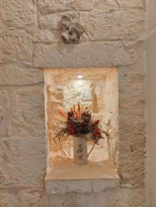 un jarrón de flores sentado en un nicho en una pared de piedra en Le Pietre Apartments, en Ostuni