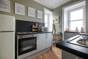 a kitchen with a sink and a refrigerator at Trendy 2 Bed Flat - Near Airport in Broxburn