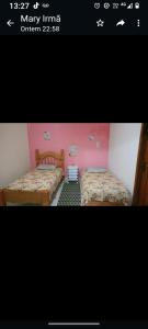 two beds in a room with pink walls at Suite familiar in Araruama