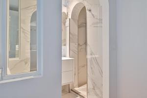 a bathroom with white marble walls and a mirror at Terrasse au coeur du Marais in Paris