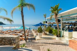 a restaurant on the beach with palm trees and the ocean at Folie Marine Hotel & Beach Club in Jal
