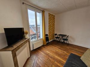 een woonkamer met een flatscreen-tv en een groot raam bij Le Weber-Paris in Pantin