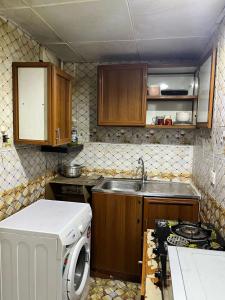 a kitchen with a sink and a washing machine at Tanih's Lodging in Abu Dhabi