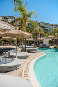 a swimming pool with chairs and umbrellas at Folie Marine Hotel & Beach Club in Jal